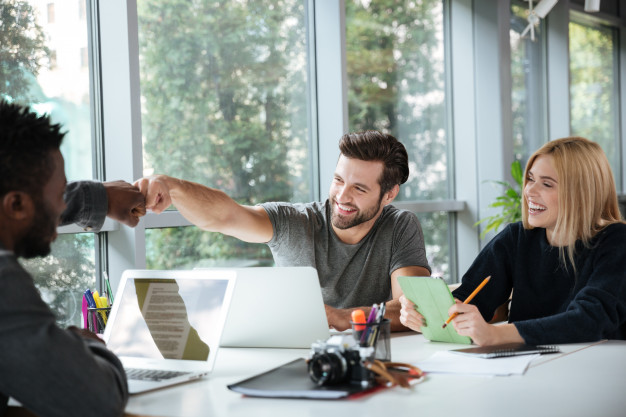 smiling-young-colleagues-sitting-office-coworking_171337-17646